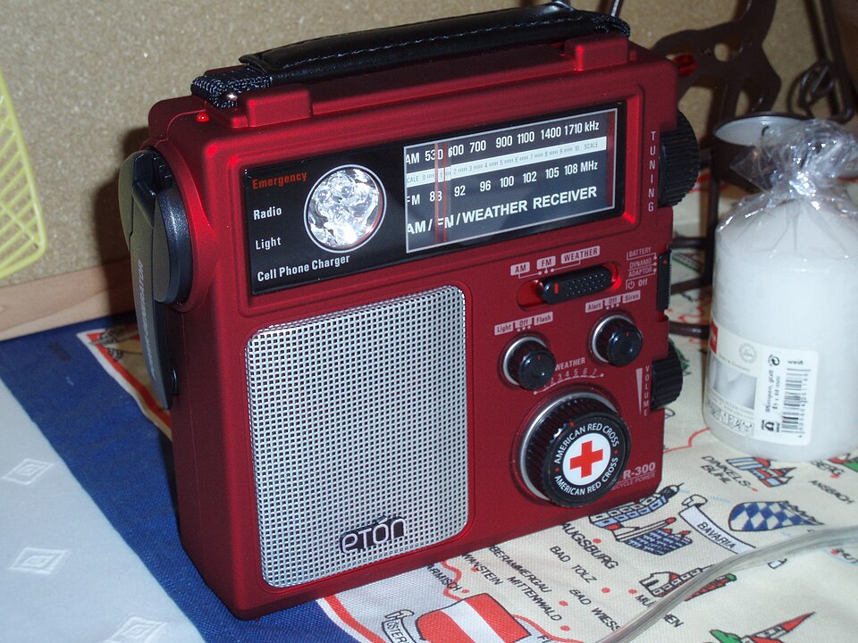 A red Eton emergency radio with a tuning dial, speaker grille and hand crank, for storm prep in Marion, IA