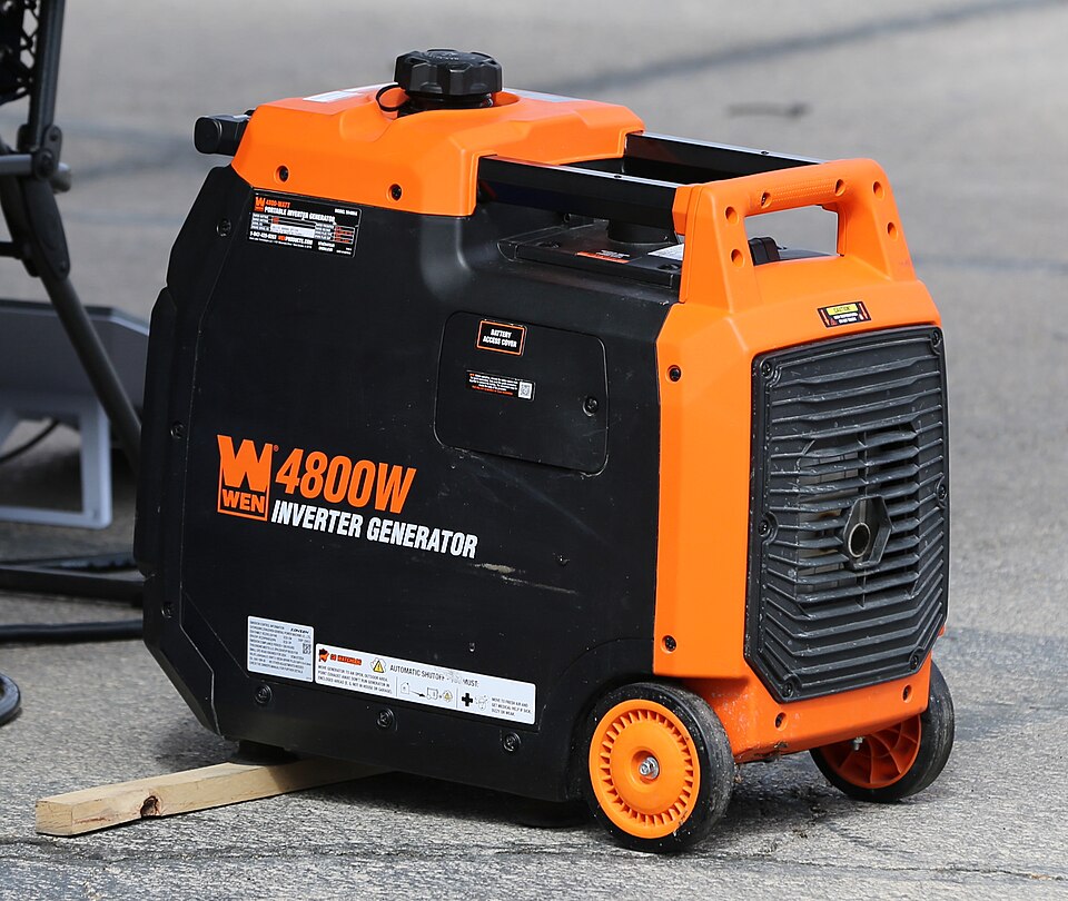 An orange and black WEN 4800 inverter generator with wheels, sitting on pavement, for storm prep in Marion, IA